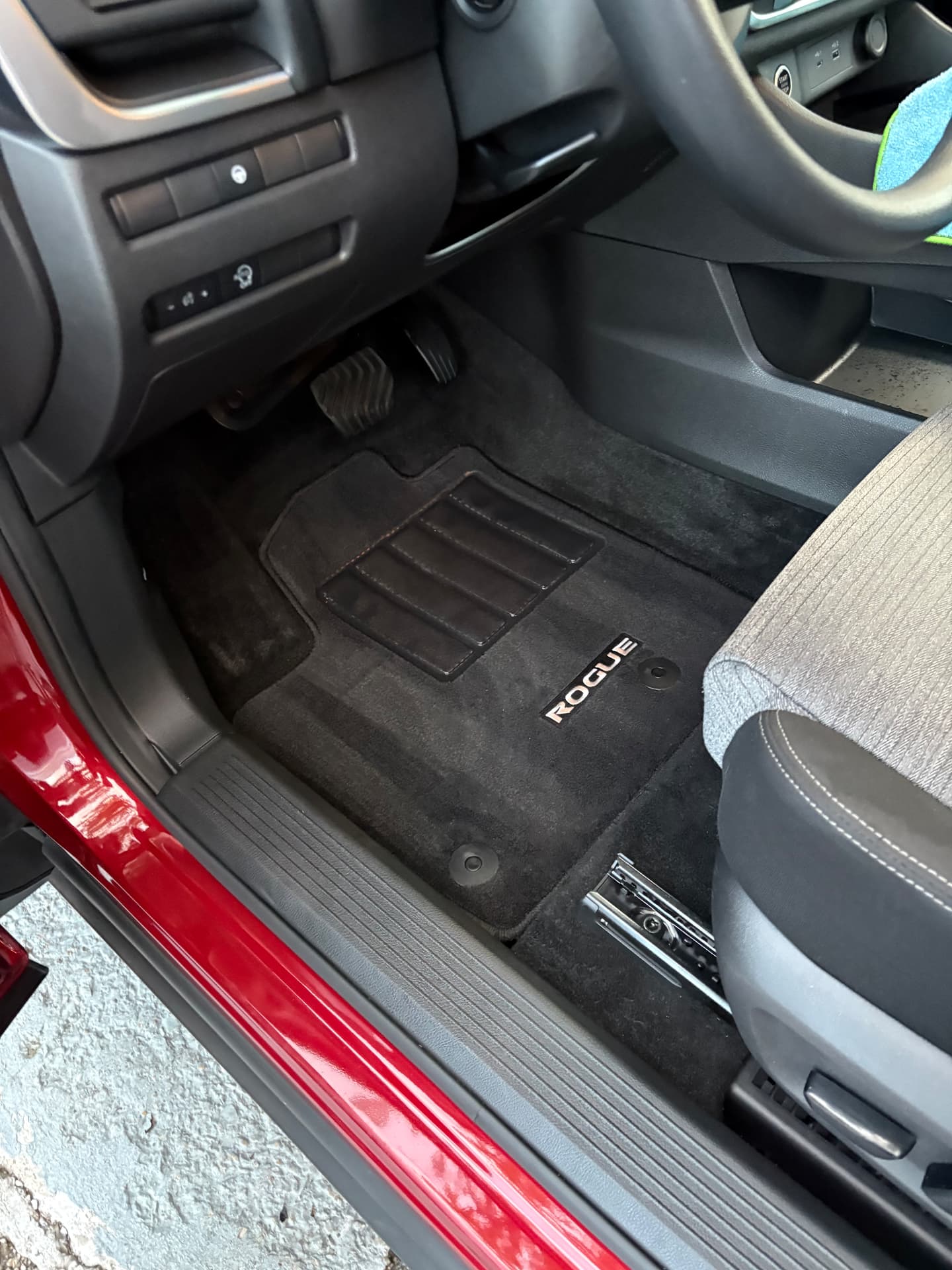 Clean driver footwell and floor mat in a red Nissan Rogue